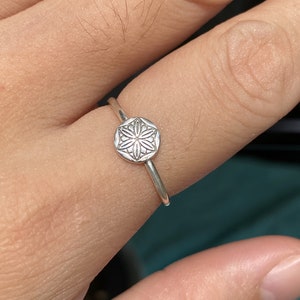 May include: A silver ring with a delicate, detailed flower design on the band.
