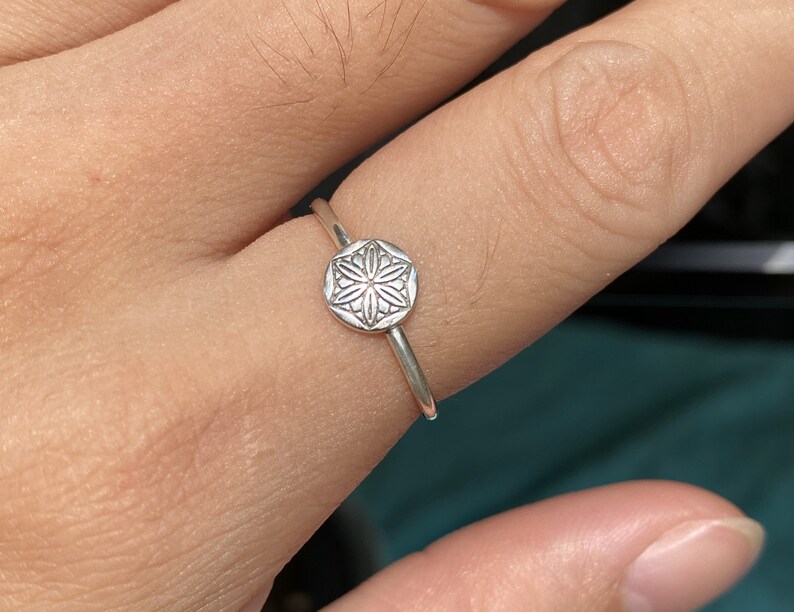 May include: A silver ring with a delicate, detailed flower design on the band.