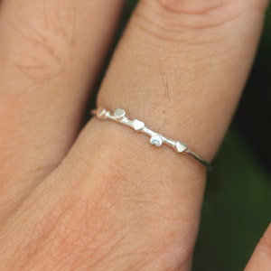 K&ouml;nnte beinhalten: Ein silberner Ring mit einem zarten Design mit kleinen herzf&ouml;rmigen Akzenten.