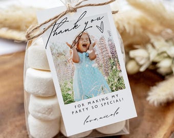 May include: A clear cellophane bag tied with twine, filled with marshmallows, and a tag that says "Thank You" with a photo of a girl. The tag also reads "For making my party so special! love, nicole."