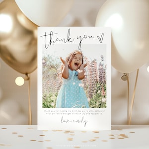 May include: A white thank you card with a photo of a girl in a blue dress, arms raised, laughing. Text reads "thank you" and "thank you for making my birthday party unforgettable! Your presence brought so much joy and happiness. love, emily."