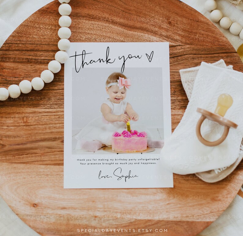 May include: A thank you card with a photo of a baby girl in a white dress, holding a lit candle on a pink cake. The card reads "thank you" and includes a personal message and signature.