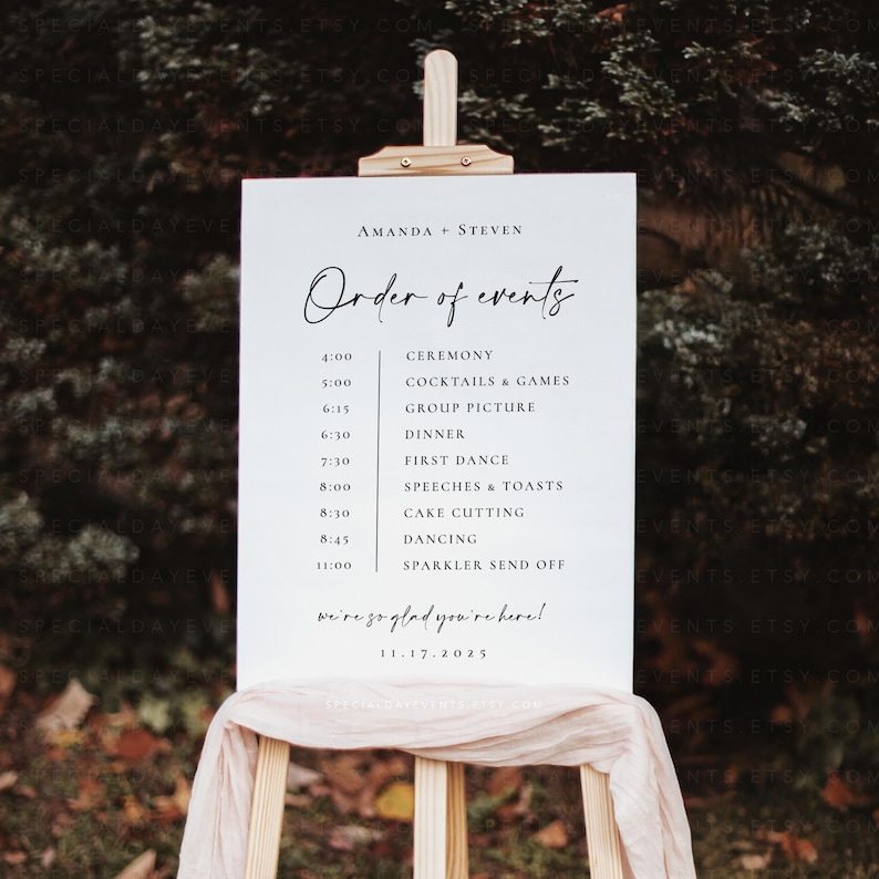 May include: A white wedding sign on a wooden easel, displaying the text "Amanda + Steven" and "Order of events." The schedule includes ceremony, dinner, dancing, and sparkler send-off. The date is 11.17.2025.