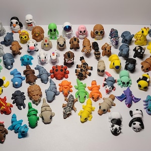 May include: A collection of over 50 colorful, small, plastic figurines of various animals, insects, and characters. The figurines are arranged in a grid pattern on a white surface.