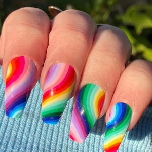 Peut inclure: Design d'art d'ongles en forme de tourbillon arc-en-ciel sur des ongles longs et en forme d'amande. Les ongles sont peints dans un motif arc-en-ciel avec un effet de tourbillon.