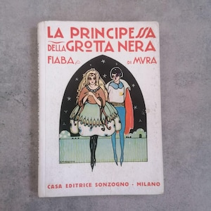 Peut inclure: Livre italien vintage intitulé "La Principessa Della Grotta Nera Fiaba di Mvra". La couverture présente une princesse et un prince dans une arche noire avec des étoiles. Le titre est en rouge, et le nom de l'éditeur est en bas.
