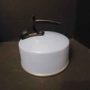 May include: A light blue enamel tea kettle with a black handle and lid. The kettle has a silver base.