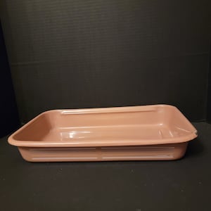 May include: A light pink rectangular baking dish with white lines around the rim.