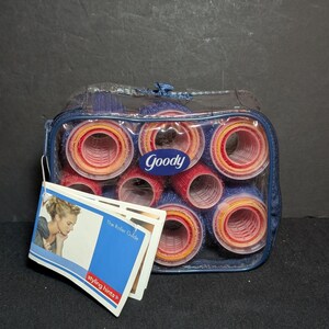 May include: A clear zippered case containing a set of Goody hair rollers. The rollers are red, blue, and yellow. A tag with the text "styling hints" and "The Roller Guide" is attached to the case.
