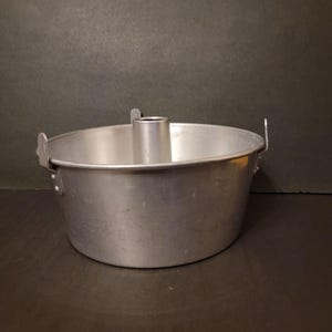 May include: A silver aluminum bundt cake pan with a removable center tube. The pan has a smooth, slightly textured surface and is designed for baking cakes with a hole in the center.