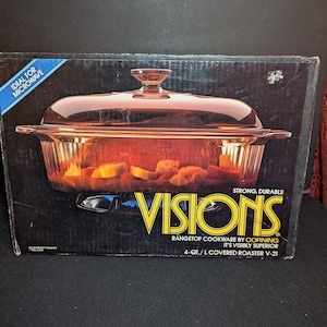 May include: A black rectangular box for a Visions 4-quart covered roaster by Corning. The box features an image of a clear glass roaster with a lid containing vegetables over a blue flame. Text includes Visions, Rangetop Cookware, and It's Visibly Superior.