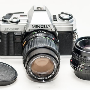ミノルタ X300 35 mmフィルムカメラ（50 mmおよび135 mmレンズ付き）