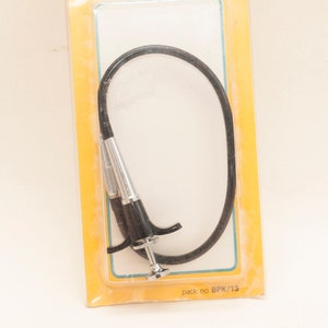 May include: A black cable camera shutter release with a silver trigger, packaged in a yellow and blue plastic bag with the text "Photoaccessories 12' Compur release pack no BPK/13"