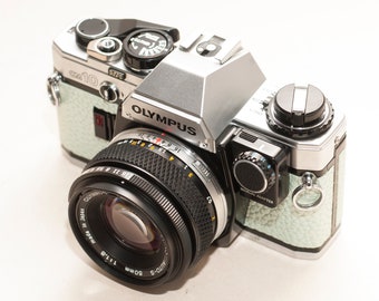 Olympus OM 10 with ZUIKO 50 mm f/1.8 lens and manual adapter - EXCELLENT. Light seledine - metalic - new skin re-covered.