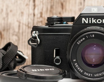 Cámara de película Nikon EM: Objetivo pancake de 50 mm f/1.8, precintos nuevos.