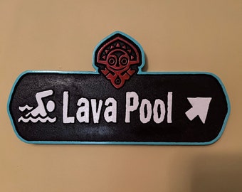 May include: A black sign with white text and a turquoise border, reading "Lava Pool" with a swimmer icon and an arrow. The sign has a decorative top with a red and turquoise design.