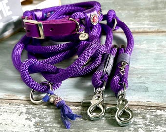 May include: A purple dog collar and leash set. The collar has a purple leather strap and silver buckle. The leash is made of thick, braided purple rope with silver clasps and a decorative charm.