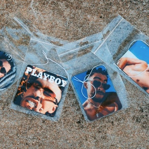 Può includere: Quattro deodoranti per ambienti in confezioni di plastica trasparente. Uno è rotondo, gli altri sono rettangolari o a forma di diamante. Ognuno presenta un uomo con occhiali da sole. Uno ha la scritta "PLAYBOY".