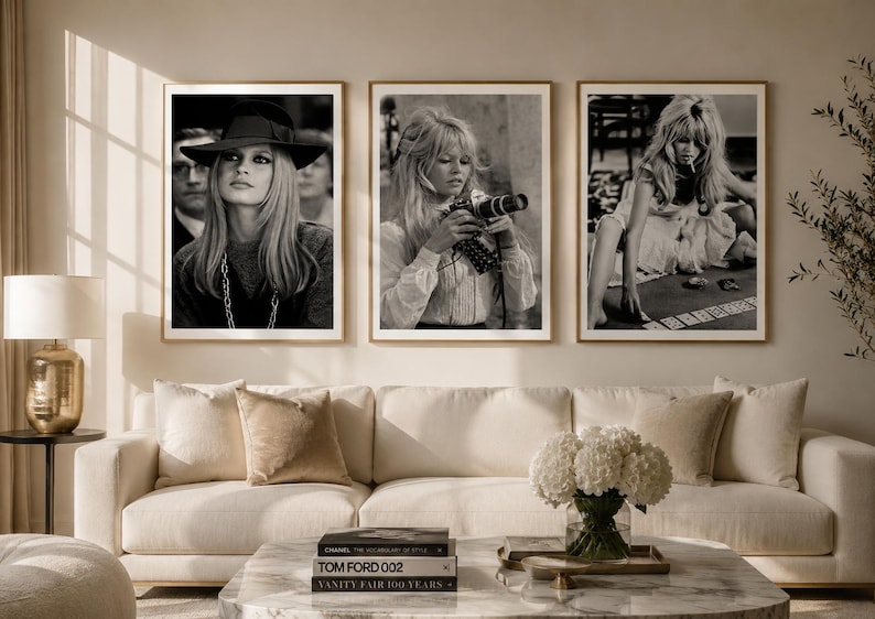 Op de afbeelding: Set van drie ingelijste zwart-witfoto's. De foto's tonen een vrouw in verschillende poses, waaronder een met een camera, een met een hoed en een zittend aan een tafel. De lijsten zijn lichtbruin en de afbeeldingen worden boven een cr&egrave;mekleurige bank weergegeven.