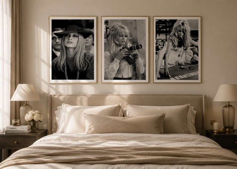 Op de afbeelding: Drie ingelijste zwart-witfoto's van een vrouw worden boven een bed getoond. De foto's tonen dezelfde vrouw in verschillende poses, waaronder een met een camera en een andere die kaarten speelt. De frames zijn goudkleurig.