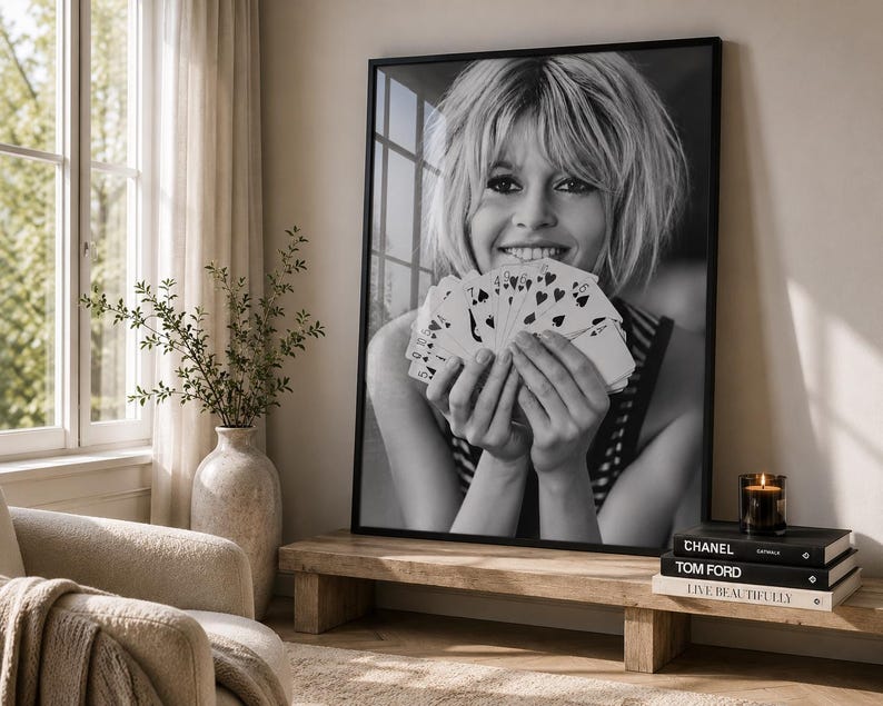 K&ouml;nnte beinhalten: Ein schwarz-wei&szlig; gerahmter Wandkunstdruck, der eine l&auml;chelnde Person mit kurzem Haar zeigt, die einen F&auml;cher aus Spielkarten h&auml;lt. Das Portr&auml;t ist in einem d&uuml;nnen schwarzen Rahmen pr&auml;sentiert und f&auml;ngt einen spontanen Moment ein.