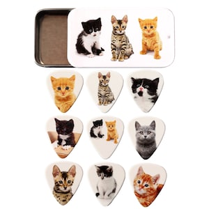 May include: A set of 10 guitar picks featuring different adorable kitten images. The picks are white with rounded edges and come in a small tin.