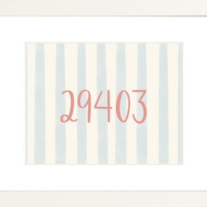 May include: A framed print featuring the number 29403 in a coral pink script font centered on a background of vertical light blue and cream-colored stripes. The artwork is enclosed within a clean white mat and a simple white frame border.