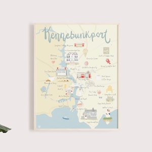 May include: A hand-drawn illustrated map of Kennebunkport, Maine, with a light blue background and a beige border. The map features various landmarks and businesses, including The Clam Shack, The Inn at Ocean's Edge, and The Nonantum Resort. The map is framed in a light wood frame.