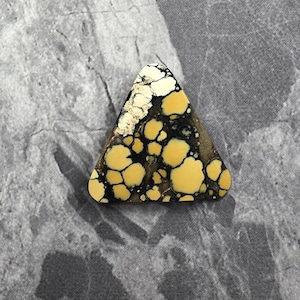 May include: A triangular-shaped gemstone featuring a mustard yellow base color with intricate, dark brown to black web-like matrix patterns throughout the surface. The stone has a smooth, polished finish and a distinct, irregular natural color variation.