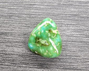May include: A green and white turquoise stone with a smooth, polished surface. The stone has a mottled pattern of green and white.