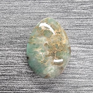 May include: A green and brown oval-shaped cabochon gemstone with a marbled pattern.