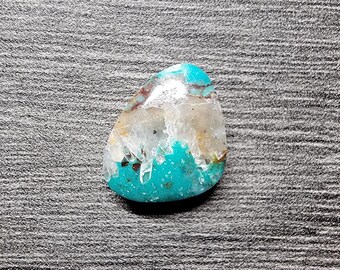 May include: A turquoise and white cabochon gemstone with a unique crystal formation. The gemstone is a natural stone with a smooth, polished surface.