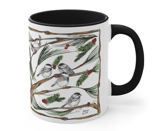 May include: White ceramic mug with a black interior and handle. The mug features a detailed illustration of several small birds perched on branches with green pine needles and red berries. The design is framed by brown branches.