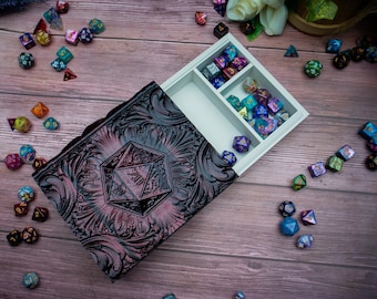 May include: A black and purple dice box with a decorative design and a removable tray with compartments for dice. The tray is filled with colorful dice.