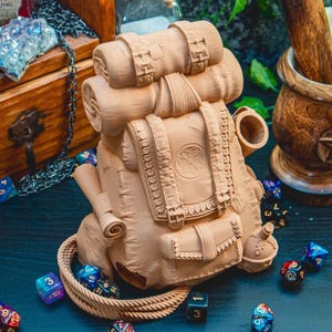 May include: A brown, detailed, 3D printed backpack with straps and buckles. The backpack is designed to look like a real backpack and has a worn, weathered appearance. The backpack is sitting on a dark blue surface with several blue and purple dice scattered around it.