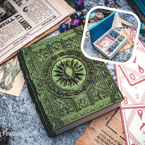 May include: An ornate green book with a sunburst design on the cover, surrounded by playing cards, dice, and a small box filled with dice. The book's cover features a detailed, embossed pattern, with a vintage aesthetic.