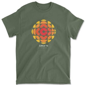 May include: A green t-shirt with a retro-style graphic of the Canadian Broadcasting Corporation logo. The logo is in shades of orange, red, and yellow. The text "CIRCA '74" is printed below the logo.