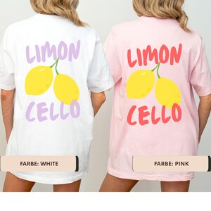 K&ouml;nnte beinhalten: Wei&szlig;e und rosa T-Shirts mit Zitronen-Design. Das wei&szlig;e Shirt hat einen lila "Limon Cello"-Aufdruck mit gelben Zitronen. Das rosa Shirt hat einen roten "Limon Cello"-Aufdruck mit gelben Zitronen. Die Shirts sind Freizeitkleidung.