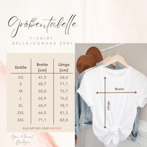 K&ouml;nnte beinhalten: Ein wei&szlig;es Bella+Canvas 3001 T-Shirt auf einem Holzkleiderb&uuml;gel. Das Bild enth&auml;lt eine Gr&ouml;&szlig;entabelle mit Ma&szlig;en in Zentimetern und den Text "ALLE ARTIKEL SIND UNISEX."