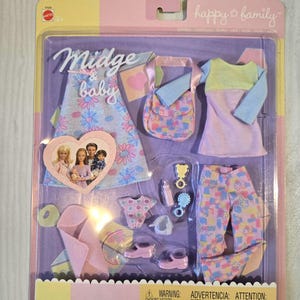 May include: A boxed doll clothing set with the words "Midge & baby" and "happy family". The set includes a dress, purse, top, pants, shoes, and baby accessories. The clothing features floral and heart patterns in pastel colors.