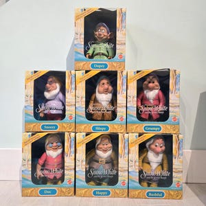 Può includere: Sette bambole vintage di Biancaneve e i Sette Nani nelle loro scatole originali. Ogni bambola è in una finestra di plastica trasparente, con il nome del nano stampato sotto. Le scatole hanno un design colorato con le parole "Biancaneve".