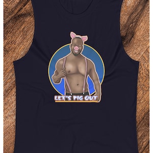 Puede incluir: Una camiseta sin mangas azul marino con un gráfico de un hombre con una nariz de cerdo y tirantes. El gráfico está en un círculo con un fondo azul y un contorno amarillo. El texto "Let's Pig Out" está debajo del gráfico.