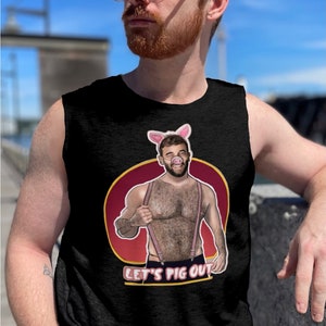 Puede incluir: Camiseta negra sin mangas con un gráfico de un hombre con una nariz de cerdo y tirantes. El gráfico está en un círculo rojo con el texto "Let's Pig Out".