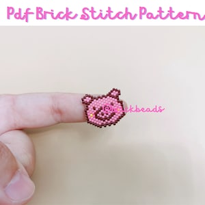 May include: A pink and brown beaded pig face charm, worn on a finger.