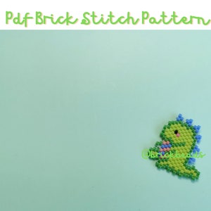 Op de afbeelding: Een groene en blauwe kralen dinosaurus met een roze hart in zijn hand. De dinosaurus is gemaakt met brick stitch kralen.