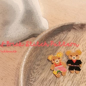 May include: Two beaded teddy bears, one wearing a pink dress and a flower crown, the other wearing a black suit and a bow tie. The bears are on a wooden plate with the text "Puff Brick Stitch Pattern @brickbeads".