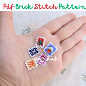 May include: Six small, colorful, square-shaped beaded ornaments with white borders. The ornaments feature various designs, including a Christmas tree, a snowflake, a gingerbread house, and a heart. The ornaments are displayed on a hand.
