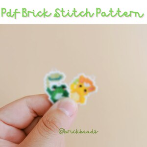 May include: A close-up of a hand holding two small pixel art patterns. The patterns are of a frog and a yellow creature. The patterns are on a white background and the text "@brickbeads" is visible in the bottom right corner.