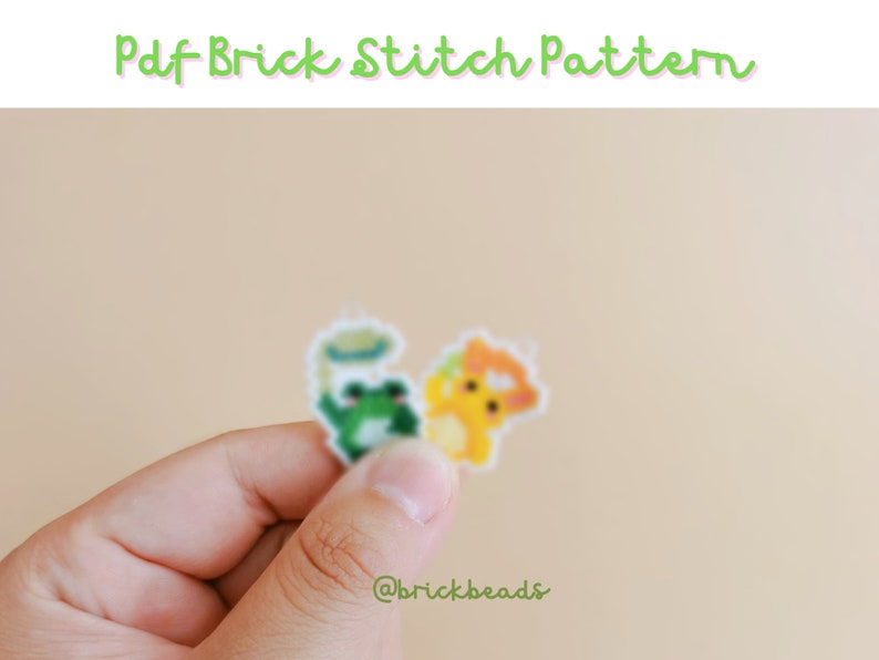 May include: A close-up of a hand holding two small pixel art patterns. The patterns are of a frog and a yellow creature. The patterns are on a white background and the text "@brickbeads" is visible in the bottom right corner.