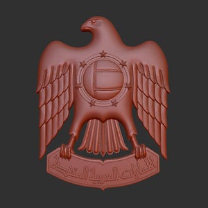 May include: A 3D printed model of the emblem of the United Arab Emirates, featuring a red falcon with outstretched wings holding a shield with seven stars and a central circle. The falcon is perched on a banner with Arabic text.